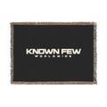 Known Few Worldwide heavyweight cotton blanket in black with a woven logo and colorful fringed edges.