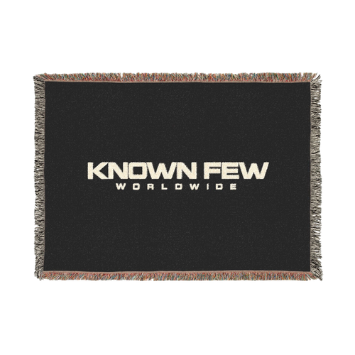 Known Few Worldwide heavyweight cotton blanket in black with a woven logo and colorful fringed edges.