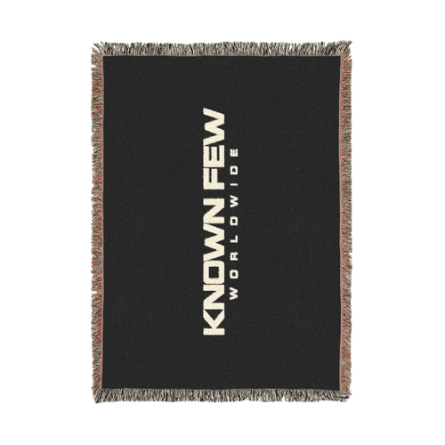 Known Few Worldwide black cotton woven blanket featuring bold white branding and colorful fringed edges.